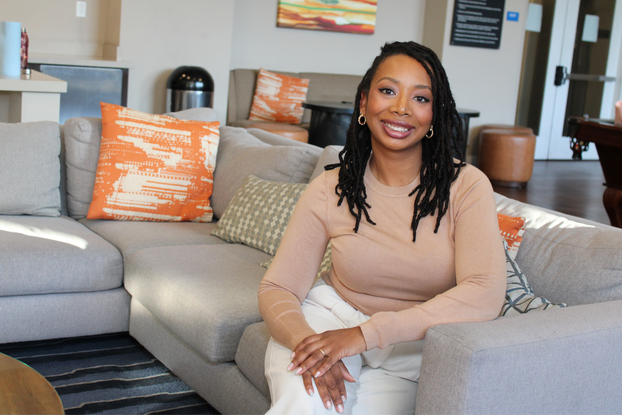 April Ornelas smiling on a couch with orange throw pillows