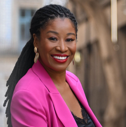 Latifah Abdur, marketing consultant, smiling in a pink blazer on a city street