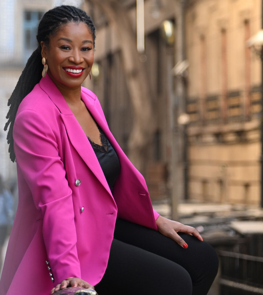 Latifah Abdur standing on a city street in a bright pink blazer