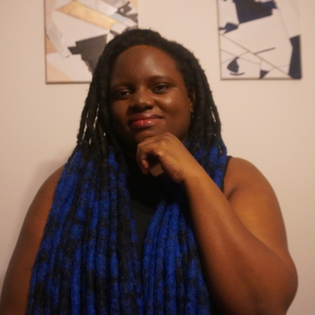 Amanda Tayte-Tait resting her chin on her hand, seated in front of abstract wall art