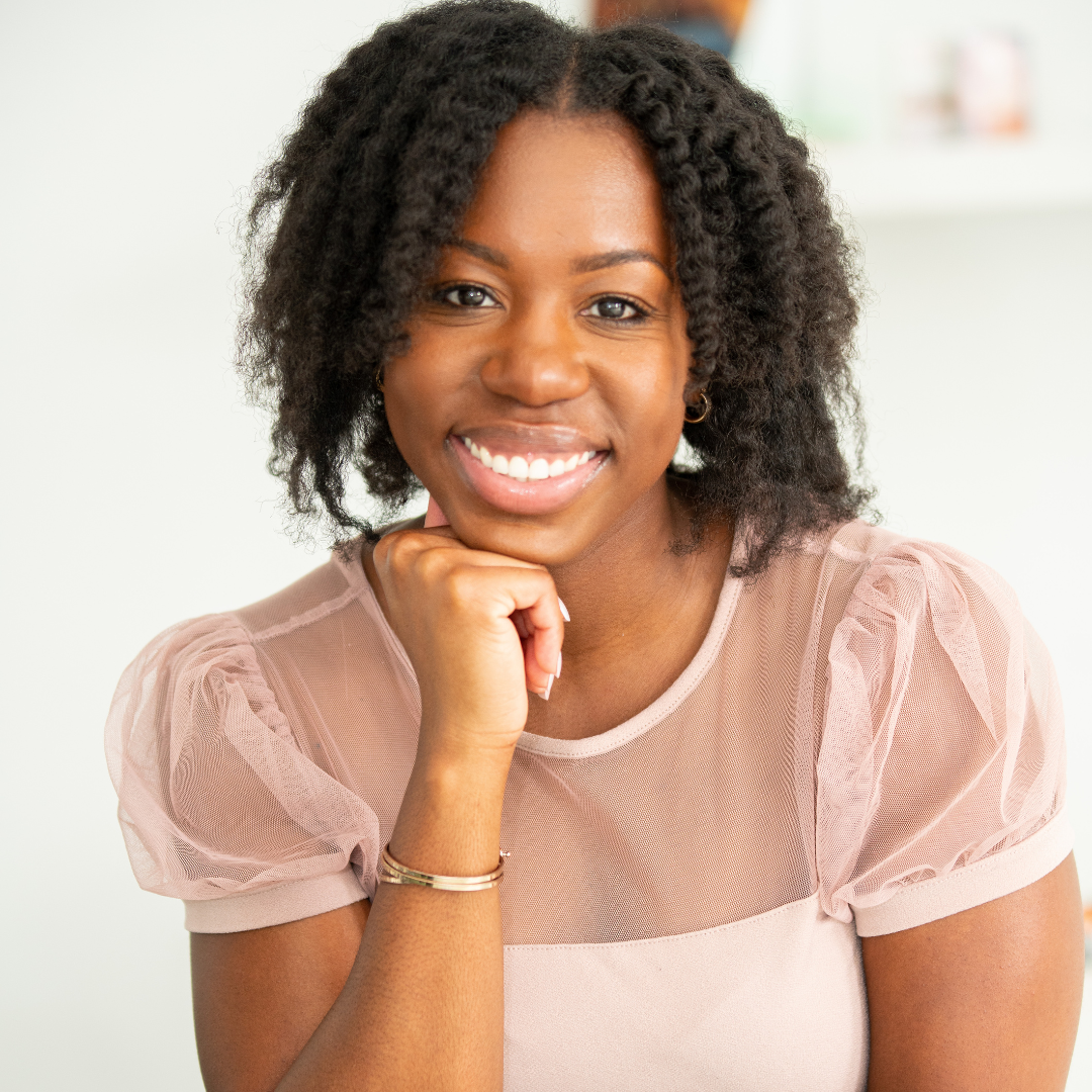 Headshot of Ashley Alleyne smiling in a blush pink blouse