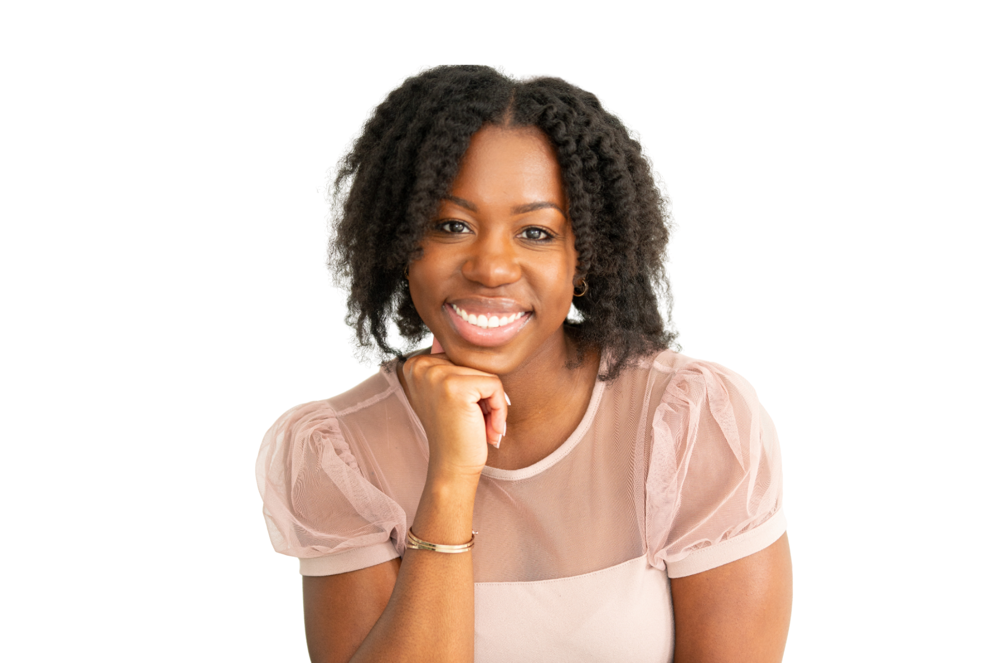 Ashley Alleyne smiling with her chin resting on her hand, wearing a blush pink blouse